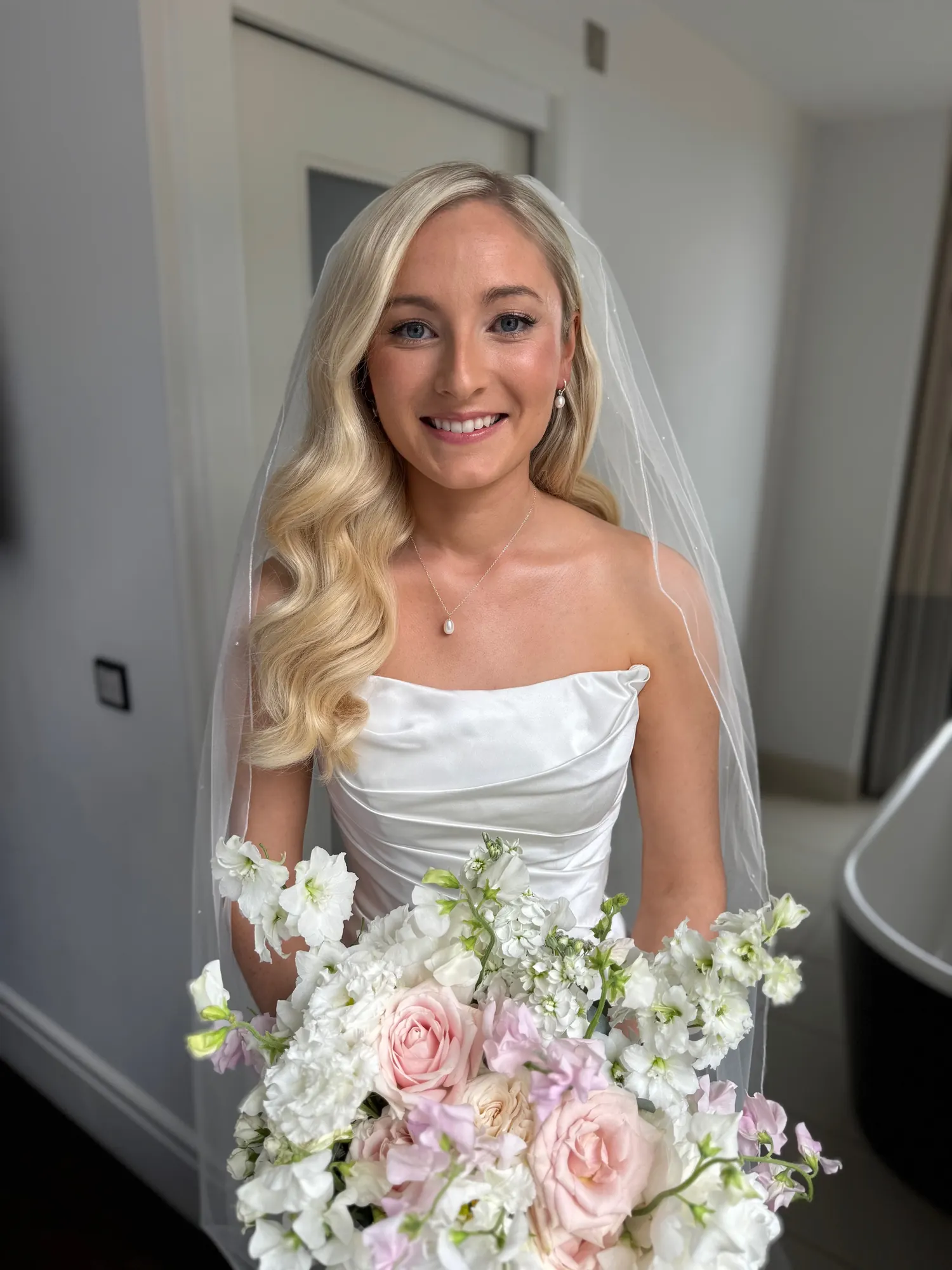 Bride with glossy side-parted blonde waves and a bouquet